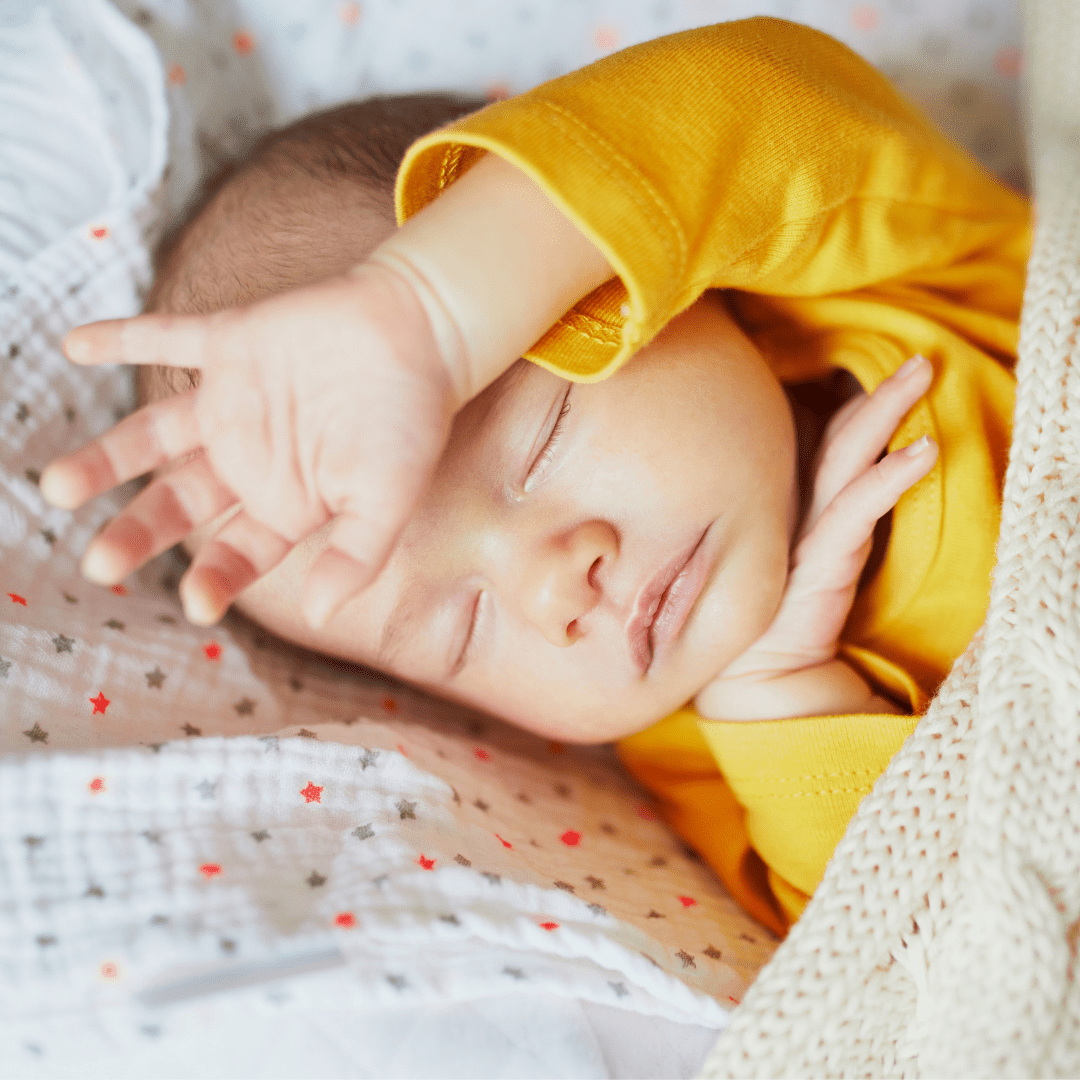 A sleeping baby in a yellow sweater